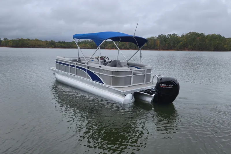 Slide: The Image of 2023 Bennington 22 SSR pontoon boat with blue canopy on a calm lake. - 6
