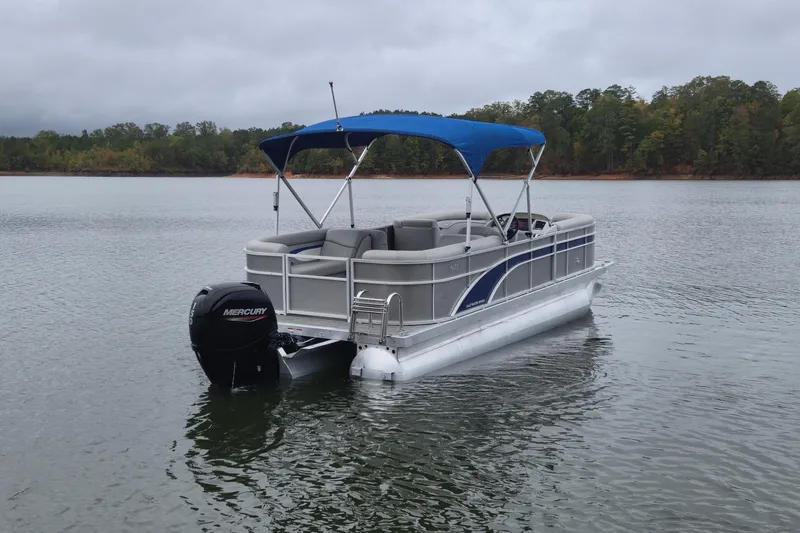 Slide: The Image of 2023 Bennington 22 SSR pontoon boat with blue canopy on a calm lake. - 8