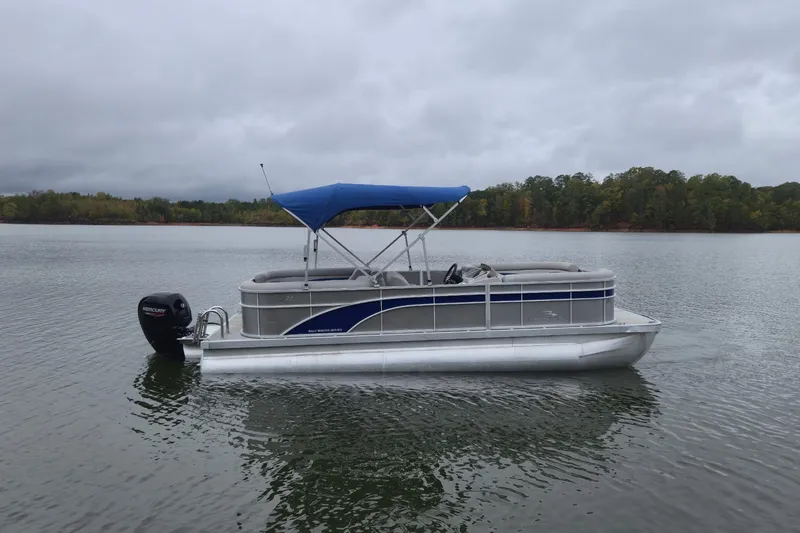 Slide: The Image of 2023 Bennington 22 SSR pontoon boat with blue canopy on a calm lake. - 9