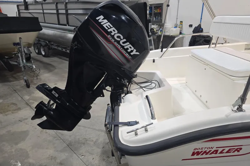 Slide: The Image of 1999 Boston Whaler Dauntless 14 with Mercury outboard motor in a garage setting. - 12