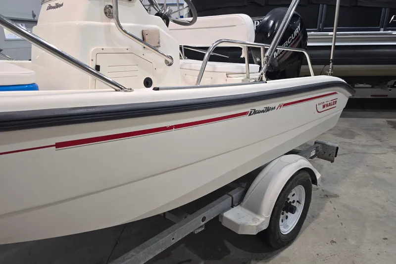 Slide: The Image of 1999 Boston Whaler Dauntless 14 boat on trailer, featuring sleek design and Mercury engine. - 24