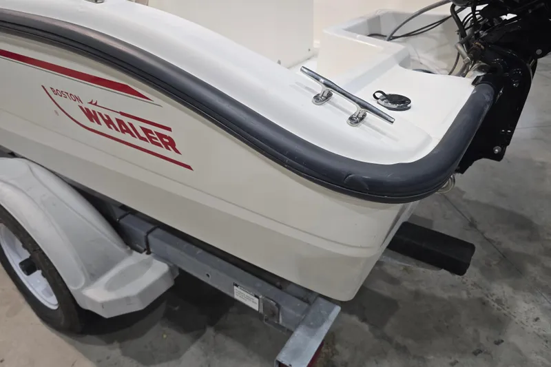 Slide: The Image of 1999 Boston Whaler Dauntless 14 boat on trailer, showcasing rear design and logo. - 26