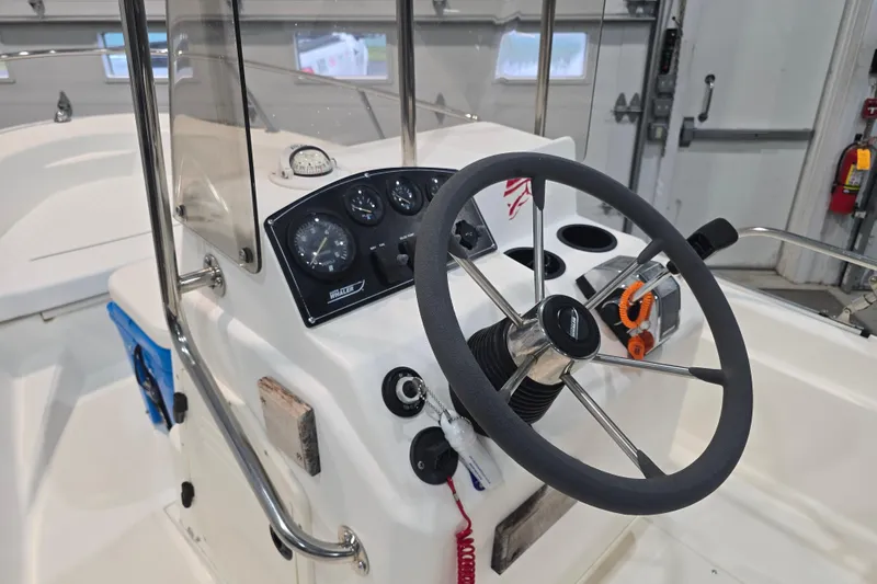 Slide: The Image of 1999 Boston Whaler Dauntless 14 boat console with steering wheel and gauges in a garage. - 29