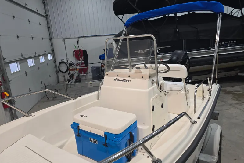 Slide: The Image of 1999 Boston Whaler Dauntless 14 boat in garage, featuring blue Yeti cooler and canopy. - 34