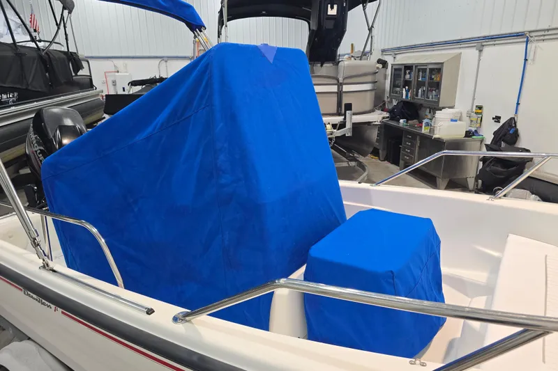 Slide: The Image of 1999 Boston Whaler Dauntless 14 boat with blue covers in a workshop setting. - 42