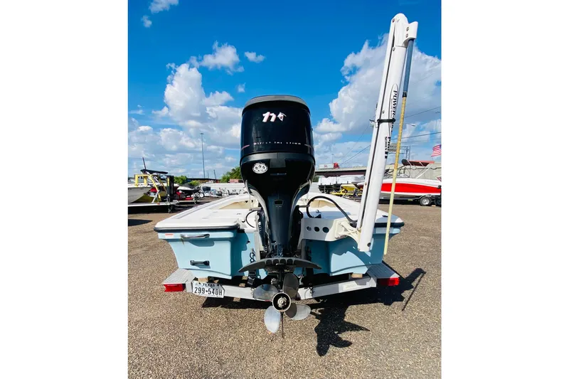 Slide: The Image of 2013 Mako 18 LTS boat with outboard motor, parked on a trailer under a blue sky. - 4