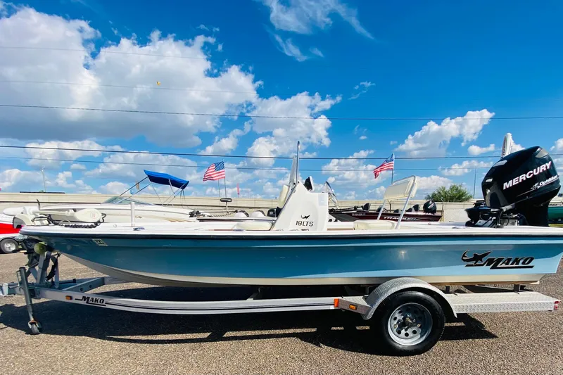 Slide: The Image of 2013 Mako 18 LTS boat on trailer, clear sky background, American flags visible. - 6