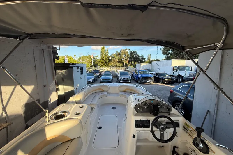 Slide: The Image of 2016 Hurricane SunDeck Sport 232 OB boat interior with steering wheel and seating, parked outdoors. - 18