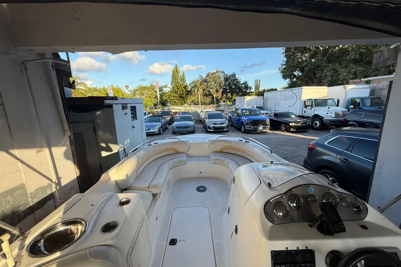 Slide: The Image of 2016 Hurricane SunDeck Sport 232 OB boat interior with parked vehicles in the background. - 27