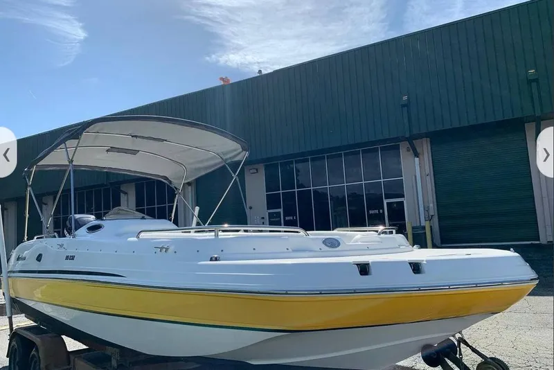 Slide: The Image of 2016 Hurricane SunDeck Sport 232 OB boat with yellow stripe, parked outside a warehouse. - 3