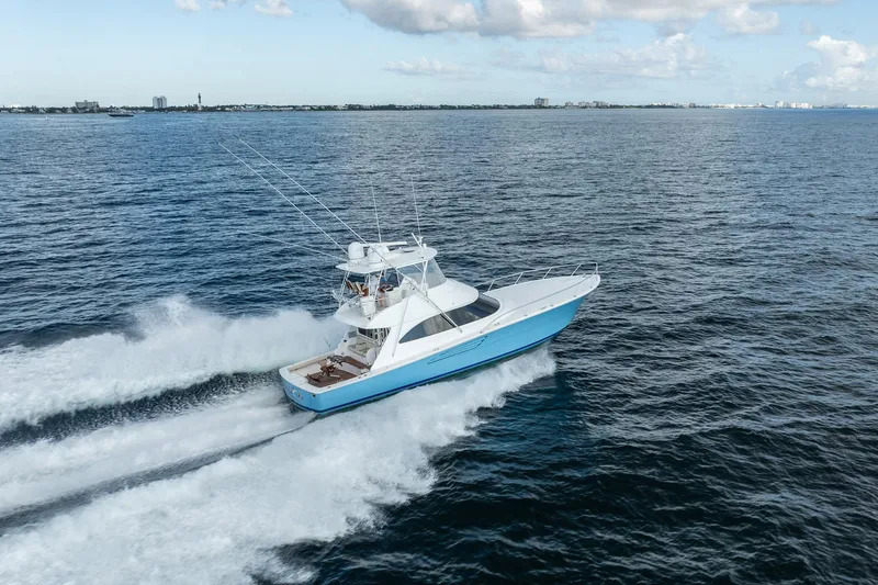 Slide: The Image of 2021 Viking 54 Convertible yacht cruising on open water under a partly cloudy sky. - 104