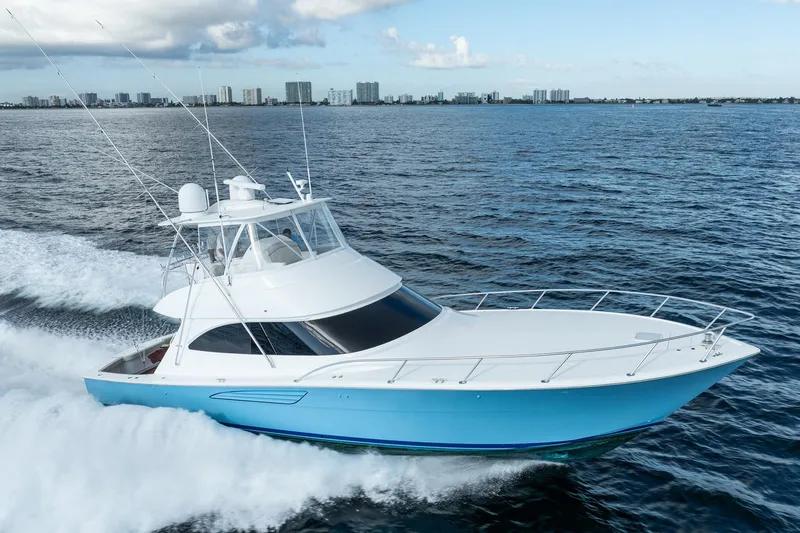 Slide: The Image of 2021 Viking 54 Convertible yacht cruising on open water, city skyline in background. - 106