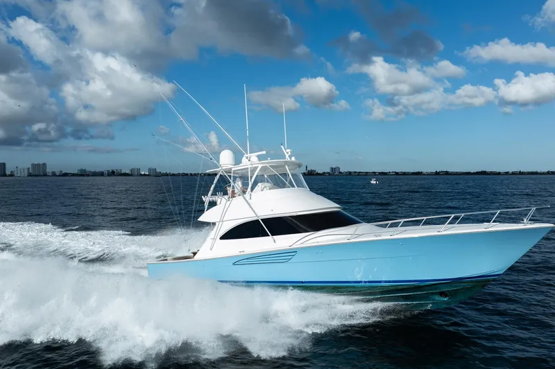 Slide: The Image of 2021 Viking 54 Convertible yacht cruising on open water under a blue sky. - 111