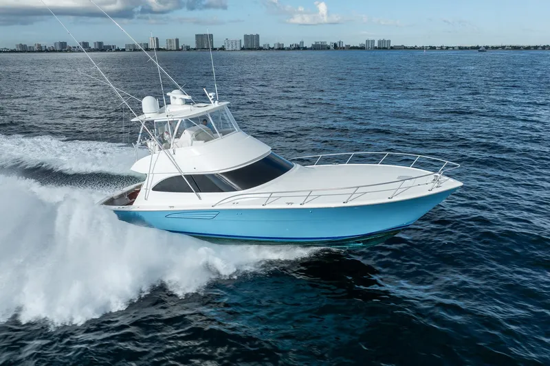 Slide: The Image of 2021 Viking 54 Convertible yacht cruising on open water, city skyline in background. - 48