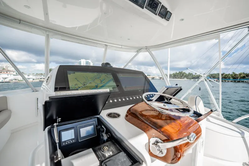Slide: The Image of Helm of 2021 Viking 54 Convertible yacht with navigation screens and steering wheel. - 60