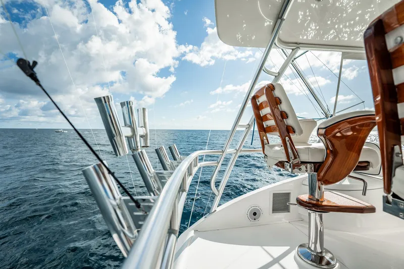 Slide: The Image of 2021 Viking 54 Convertible yacht with fishing rod holders, ocean view, and wooden chairs. - 72