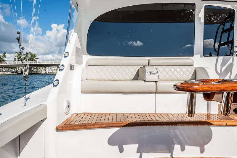 Slide: The Image of 2021 Viking 54 Convertible yacht interior with cushioned seating and wooden table. - 77