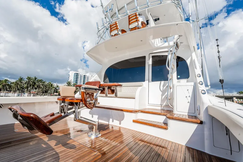 Slide: The Image of 2021 Viking 54 Convertible yacht with teak deck and fishing chair, under a partly cloudy sky. - 81