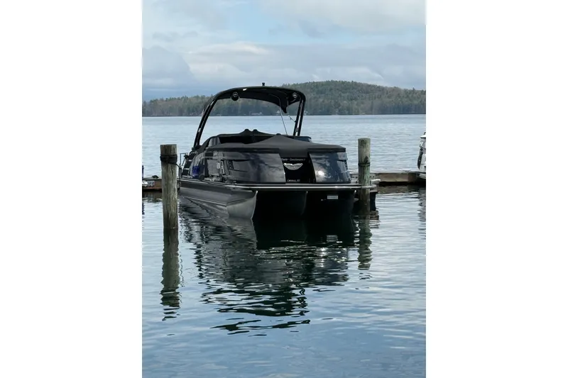 Slide: The Image of 2023 Bennington QX 25 QXSBWA pontoon boat docked on a serene lake. - 2
