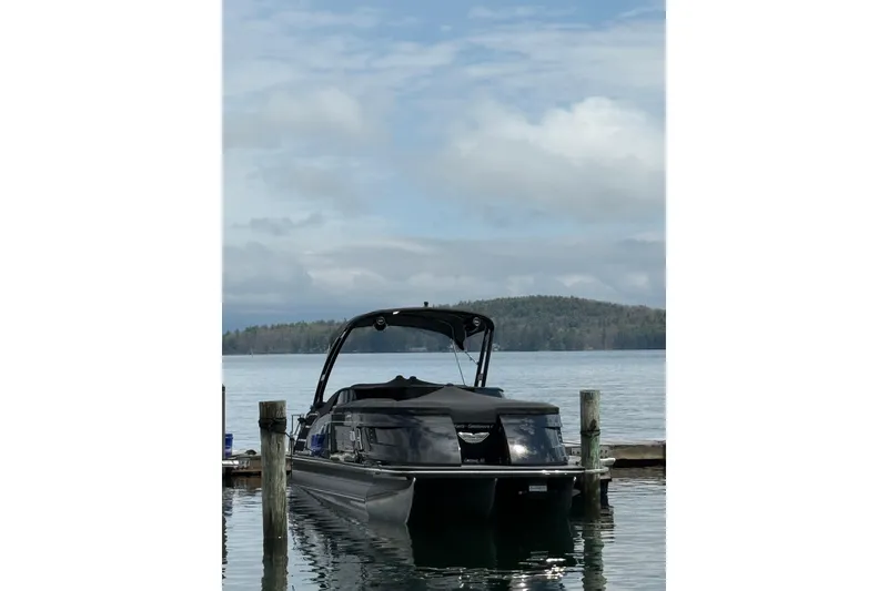 Slide: The Image of 2023 Bennington QX 25 QXSBWA pontoon boat docked on a serene lake. - 3