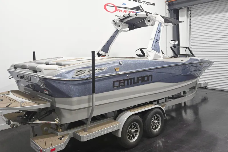 Slide: The Image of 2026 Centurion Nv243 boat on trailer in showroom, featuring sleek design and modern features. - 4