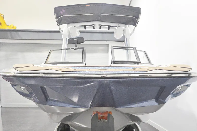 Slide: The Image of 2026 Centurion Nv243 boat in showroom, front view with sleek design and canopy. - 6
