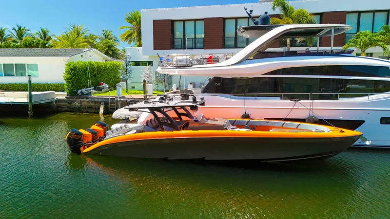 Slide: The Image of 2022 Midnight Express 43 Open boat docked beside a luxury yacht in a sunny marina. - 1