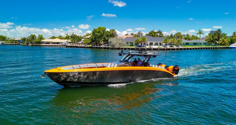 Slide: The Image of 2022 Midnight Express 43 Open boat cruising on a sunny day, surrounded by palm trees and waterfront homes. - 12
