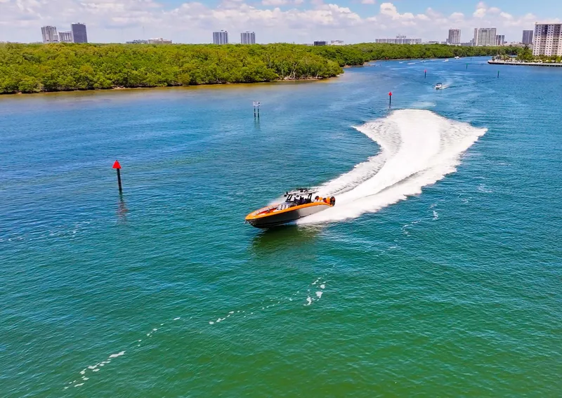 Slide: The Image of 2022 Midnight Express 43 Open speeding on a scenic waterway with city skyline backdrop. - 15
