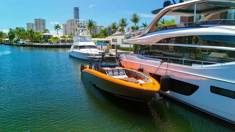 Slide: The Image of 2022 Midnight Express 43 Open boat docked beside luxury yachts in a sunny marina. - 36