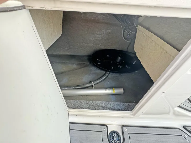 Slide: The Image of 2024 Starcraft SVX 230 OB storage compartment with hose and metal rod. - 22