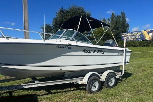 The Image of 2000 Angler Dual Console boat on trailer, parked on grass under clear blue sky. - 0