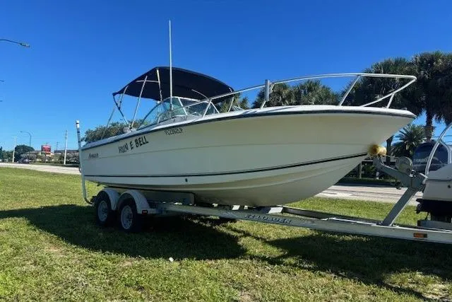 Slide: The Image of 2000 Angler Dual Console boat on trailer, parked on grass under clear blue sky. - 2