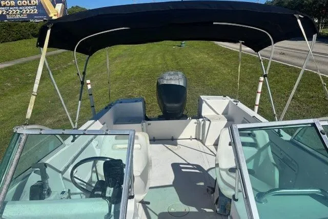 Slide: The Image of 2000 Angler Dual Console boat with canopy, parked on grass, featuring a central steering wheel. - 8