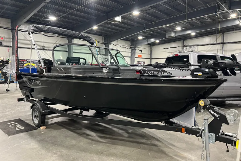 The Image of 2024 Lund 1650 Angler Sport boat in showroom, black exterior, on trailer. - 0