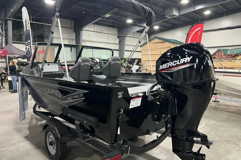 Slide: The Image of 2024 Lund 1650 Angler Sport boat with Mercury engine displayed indoors. - 2