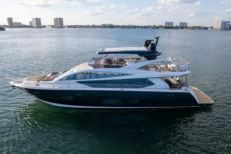 Slide: The Image of Luxurious 2020 Pearl 80 yacht cruising on calm waters with city skyline backdrop. - 11