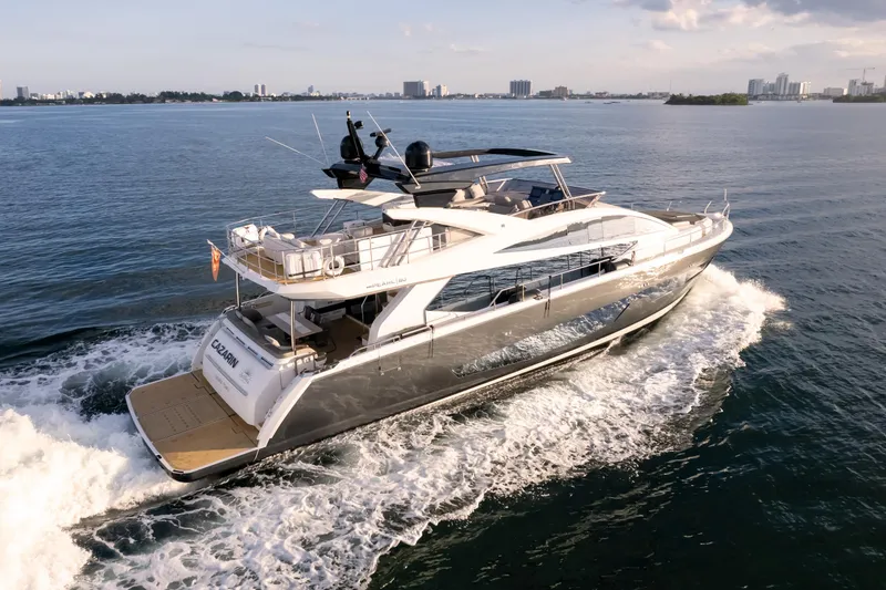 Slide: The Image of Luxurious 2020 Pearl 80 yacht cruising on open water with city skyline in background. - 5