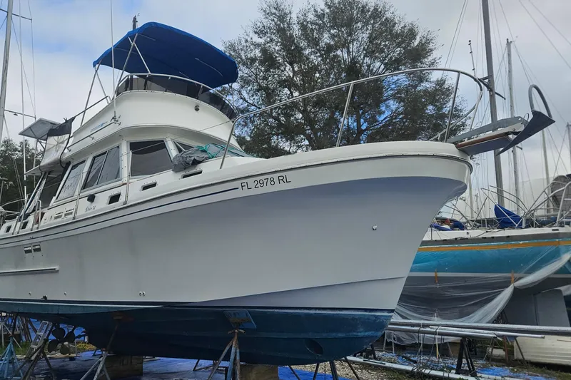 Slide: The Image of 1988 Albin 34 Cruiser boat on dry dock, with blue canopy and visible registration number. - 2