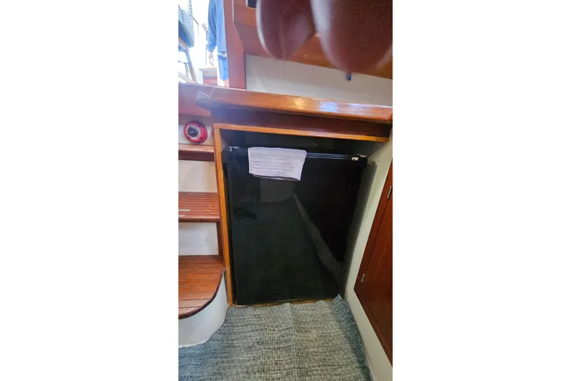 Slide: The Image of 1988 Albin 34 Cruiser interior with compact black refrigerator and wooden cabinetry. - 48