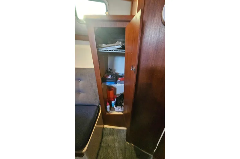 Slide: The Image of Interior of 1988 Albin 34 Cruiser showing open wooden cabinet with shelves. - 50
