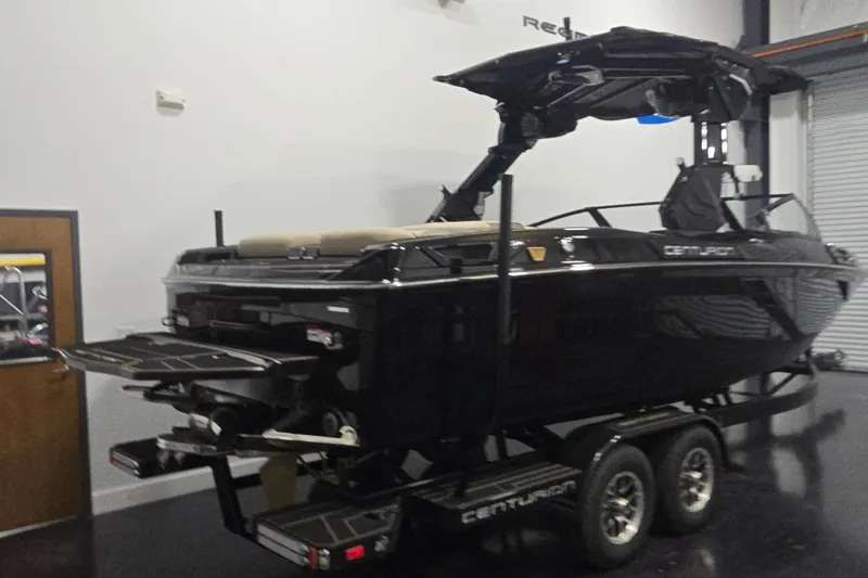 Slide: The Image of 2026 Centurion R1245 boat in showroom, sleek black design on trailer. - 3