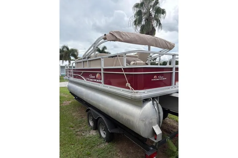 The Image of 2019 Sun Tracker Fishin' Barge 20 DLX pontoon boat on trailer, parked outdoors. - 0