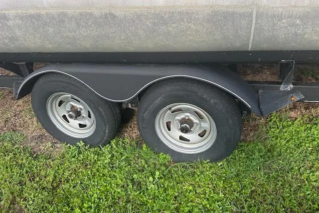 Slide: The Image of 2019 Sun Tracker Fishin' Barge 20 DLX trailer wheels on grass. - 8