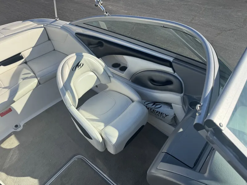 Slide: The Image of Interior of a 2009 Monterey 194FS boat with white seating and steering area. - 19