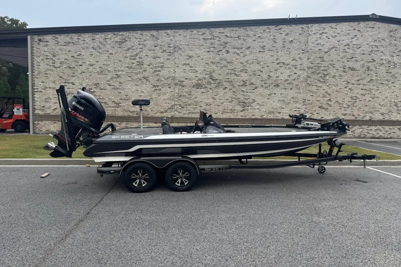 Slide: The Image of 2019 Skeeter ZX250 boat on trailer, parked outdoors near a brick building. - 0