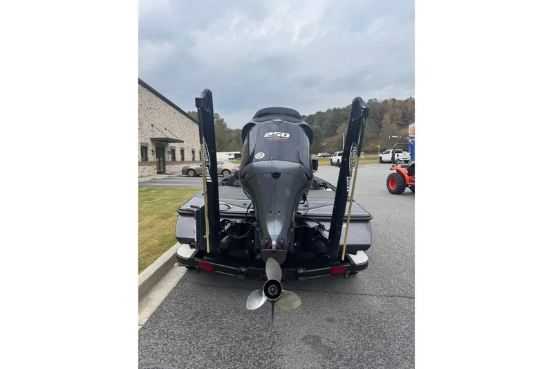 Slide: The Image of 2019 Skeeter ZX250 boat rear view with motor and power poles in parking lot. - 14