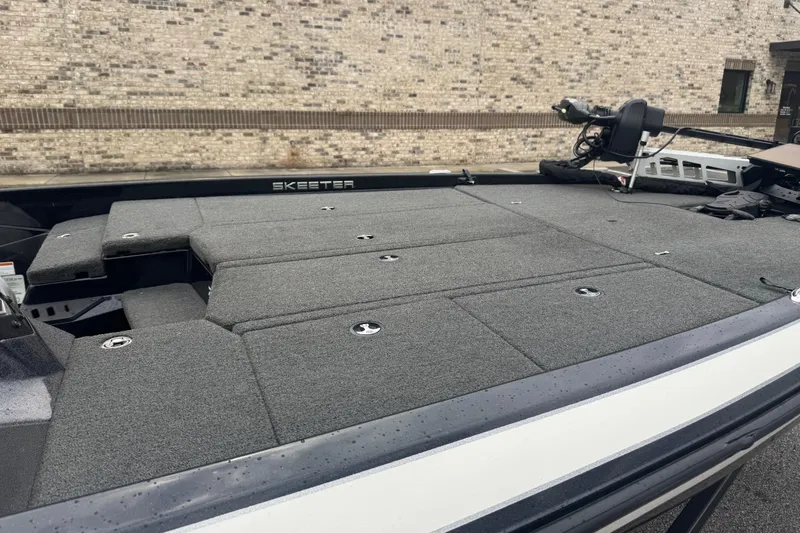 Slide: The Image of 2019 Skeeter ZX250 boat with gray deck, parked near a brick wall. - 4