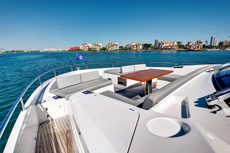 Slide: The Image of 2024 Sunseeker 76 Yacht deck with seating and table, overlooking coastal cityscape. - 23