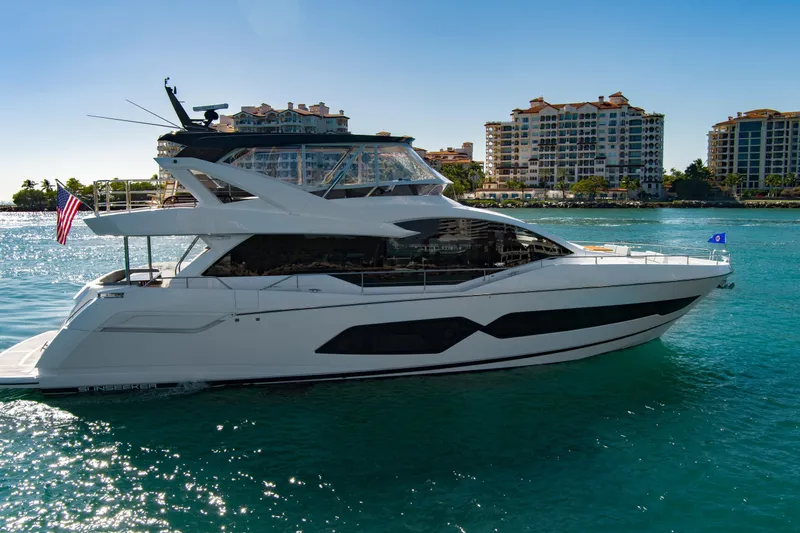 Slide: The Image of 2024 Sunseeker 76 Yacht cruising in sunny waters near luxury waterfront buildings. - 4